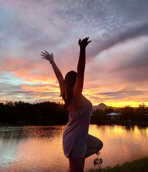 Person standing in a strong yoga pose outdoors at sunset.