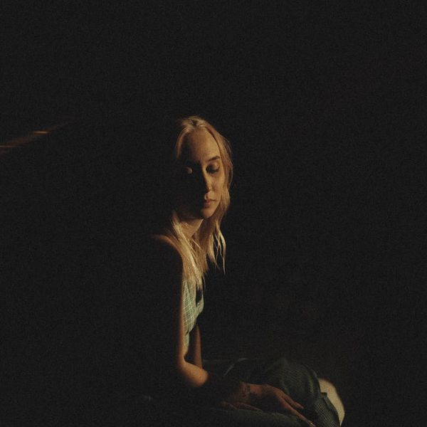 Woman sitting peacefully with her eyes closed in a calm setting.